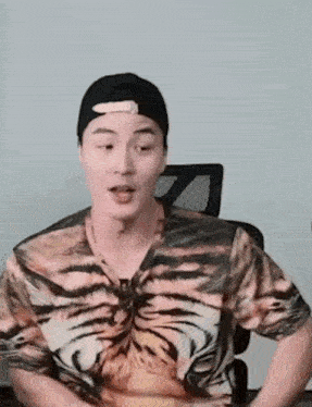 a man wearing a tiger print shirt and a hat is sitting in a chair .