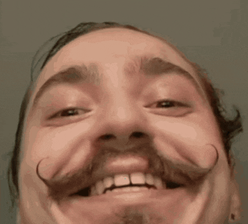 a close up of a man 's face with a mustache smiling .