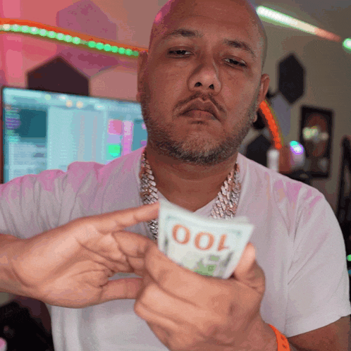a man in a white shirt is holding a stack of 100 dollar bills