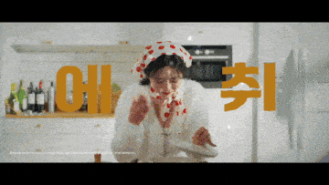 a woman in a kitchen wearing a polka dot head scarf eating a plate of food with the letters oh in the background