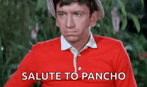 a man wearing a red shirt and a hat is standing in front of a sign that says `` salute to pancho '' .