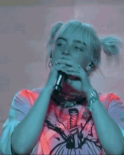 billie eilish is singing into a microphone while wearing pigtails