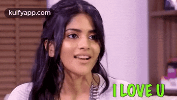 a woman is smiling and says `` i love u '' while sitting on a couch .