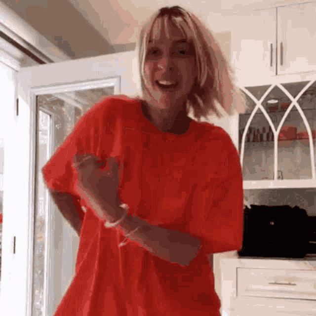 a woman in a red t-shirt is dancing in a room