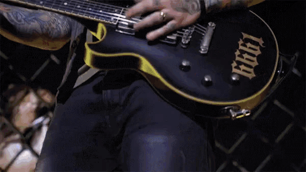a man with tattoos is playing a guitar with the word 666 written on it