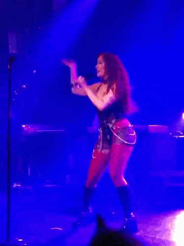 a woman singing into a microphone while dancing on a stage