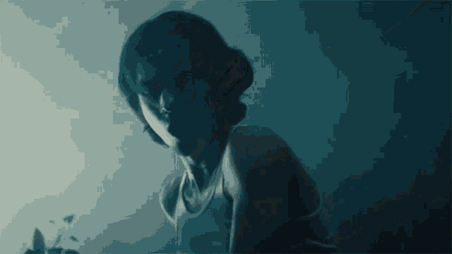 a woman in a tank top is looking at the camera in the dark .