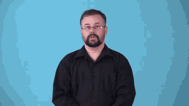 a man wearing glasses and a black shirt is making a gesture with his hands
