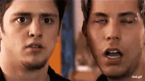 two men are looking at each other with their eyes closed and one is making a funny face .