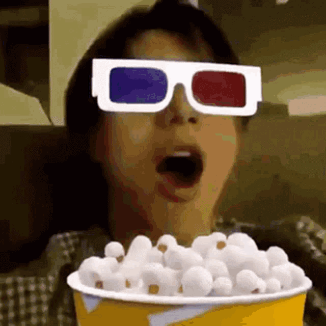 a person wearing 3d glasses and eating popcorn
