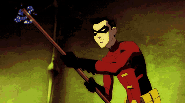 a man in a red robin costume holds a stick