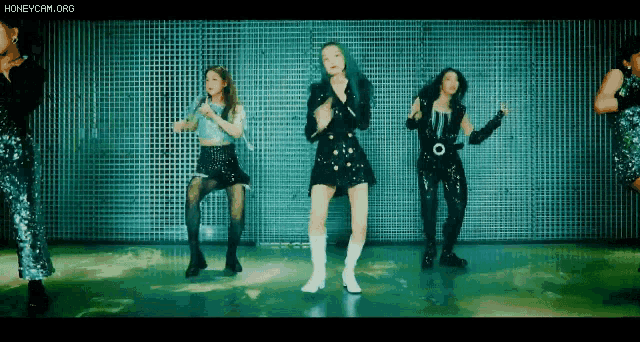 a group of women are dancing together in front of a metal wall .
