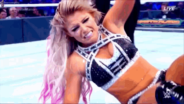 a female wrestler is laying on the ground during a match .
