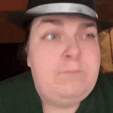 a close up of a woman wearing a hat and a green shirt .