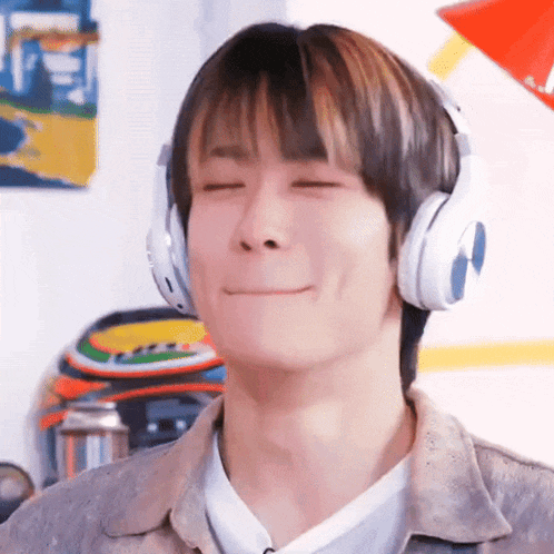 a young man wearing headphones and making a funny face .