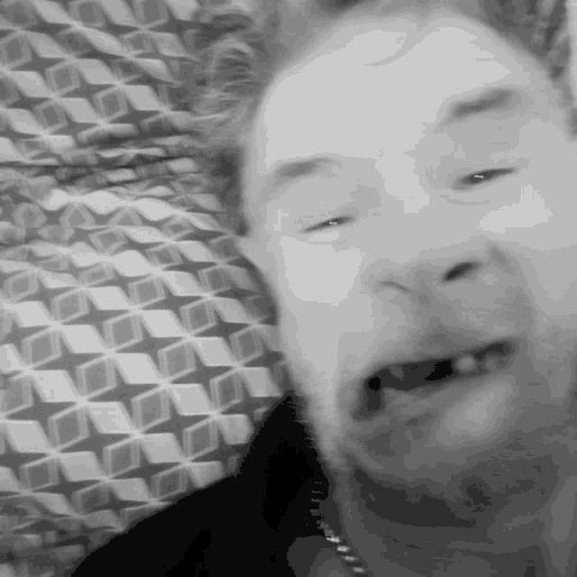 a man is making a funny face in front of a patterned blanket