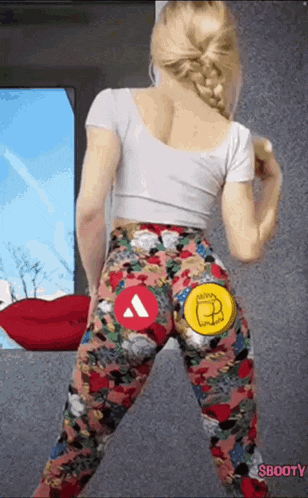 a woman wearing a white top and floral leggings is dancing