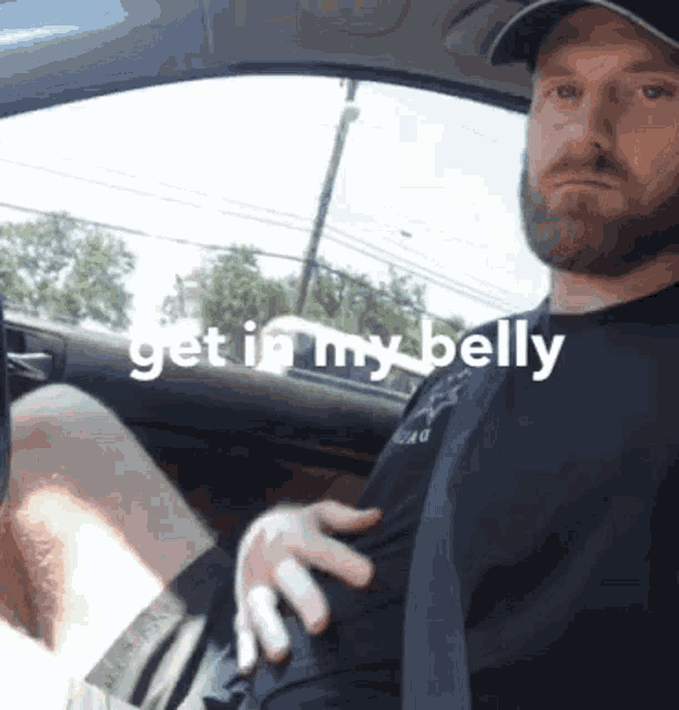 a man sitting in a car with the words get in my belly on the bottom