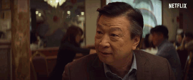 a man sitting in a restaurant with a netflix logo on the bottom right