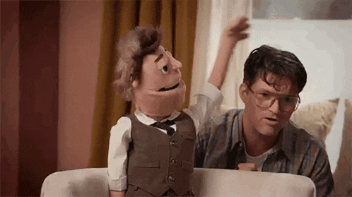 a man and a puppet are sitting on a couch .