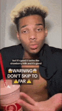 a man is holding a cup of strawberry milk and a warning sign is above him