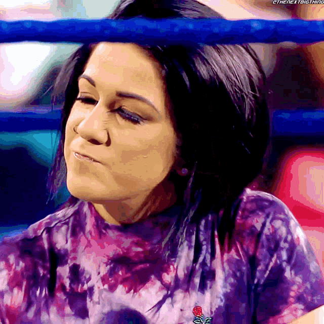 a woman wearing a purple tie dye shirt is in a boxing ring