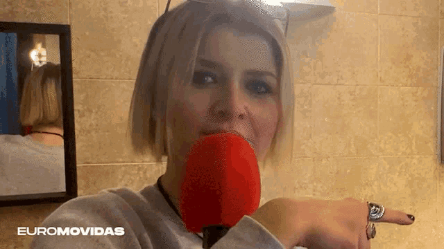 a woman holding a red object in her mouth with euromovidas written on the bottom right