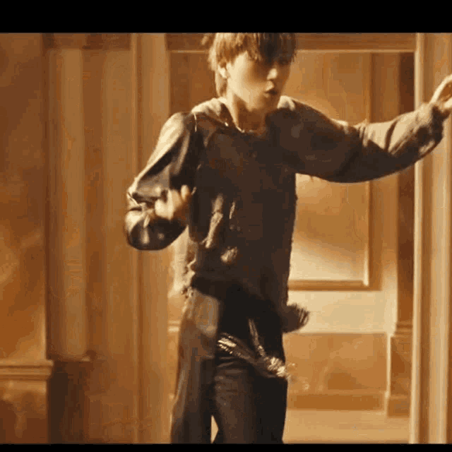 a young man is dancing in a hallway while wearing a black sweater and black pants .