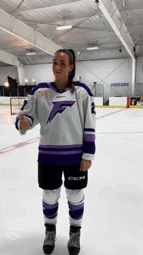a woman wearing a white and purple ccm hockey jersey