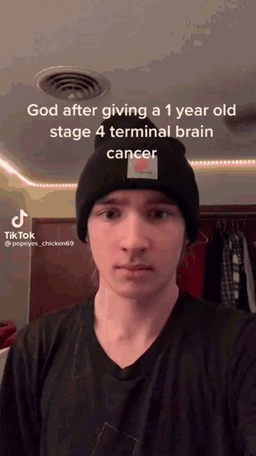 a young man wearing a black beanie and a black shirt says god after giving a year old stage 4 terminal brain cancer