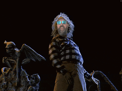 a man in a plaid shirt and sunglasses stands in front of a statue