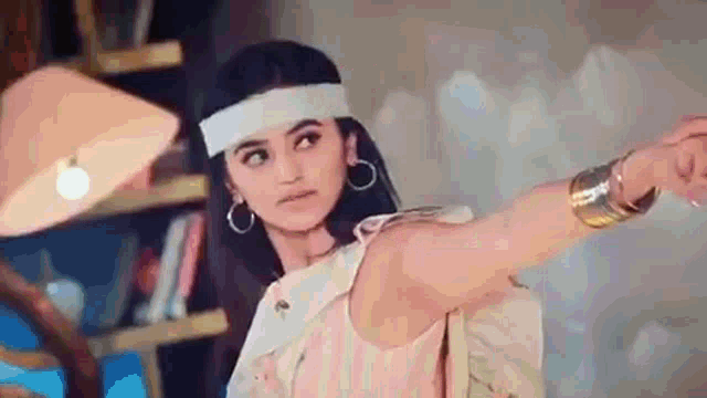 a woman wearing a headband and earrings is taking a picture of herself in a room .