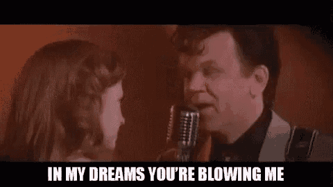 a man is singing into a microphone while a woman watches .
