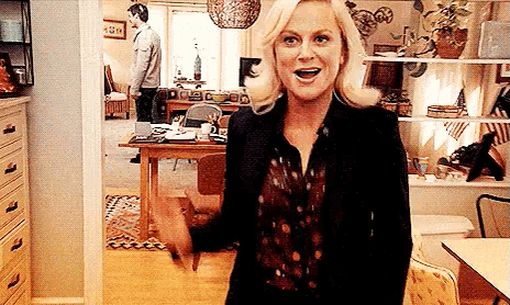 a woman is standing in a living room with her arms outstretched and smiling .