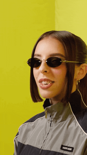a woman wearing sunglasses and a miu miu jacket smiles