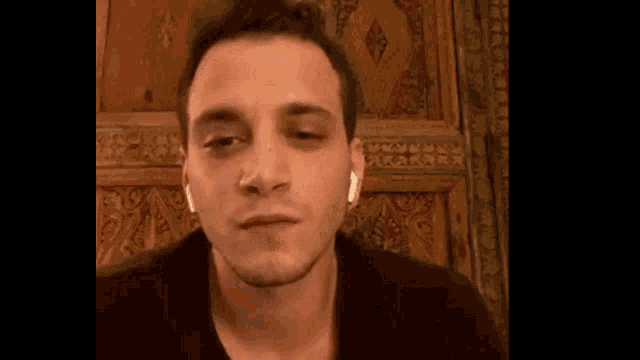 a man with a black eye is wearing ear buds and making a funny face .
