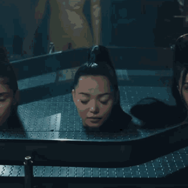 two women laying in a bathtub with their heads in the water