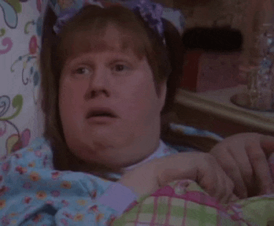 a woman is making a funny face while laying in bed with her mouth open .