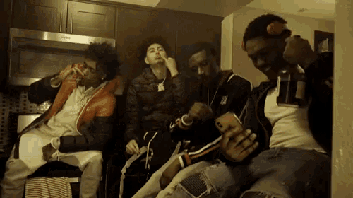 a group of young men are sitting in a kitchen with a whirlpool microwave in the background