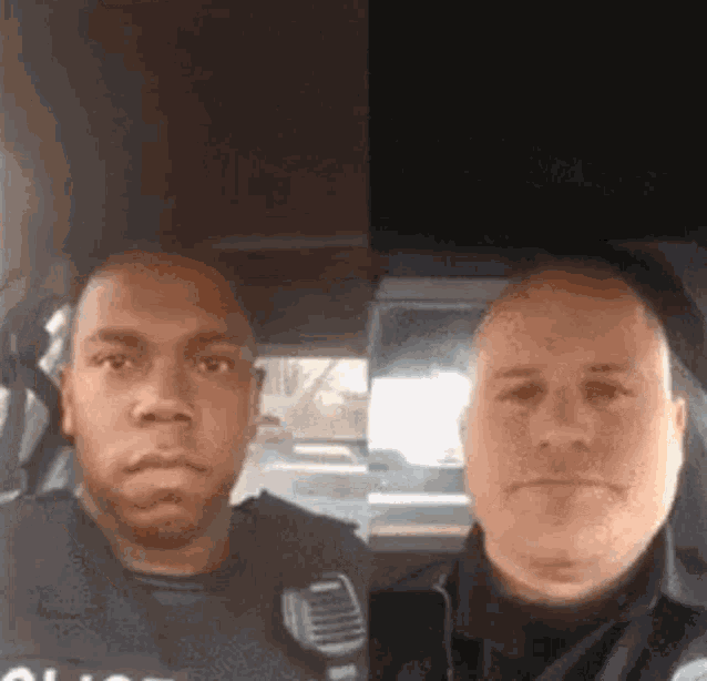 two police officers are standing next to each other in a car .