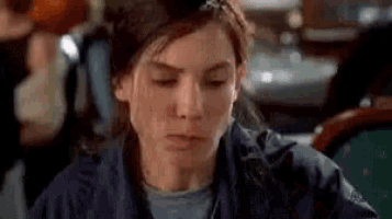 a woman is sitting at a table with her eyes closed and making a face .
