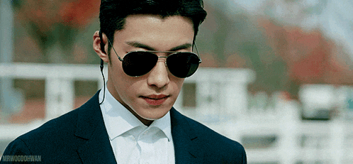 a man wearing sunglasses and a suit is looking at something