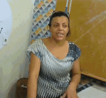 a woman wearing sunglasses and a striped shirt is sitting in front of a chalkboard