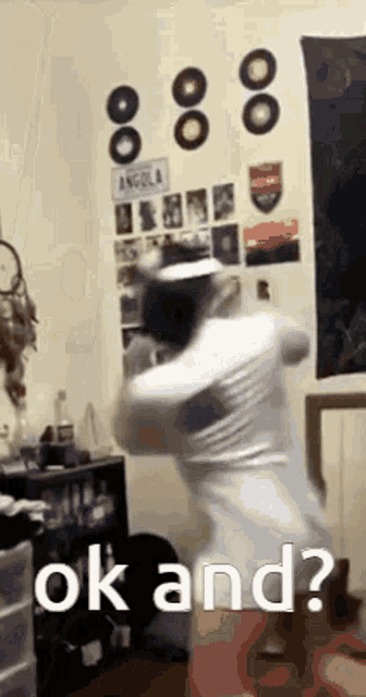a man is dancing in a room with the words `` ok and ? '' written on the wall .