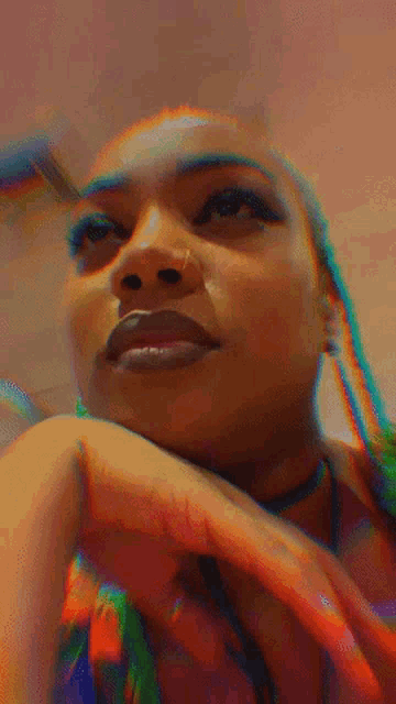 a close up of a woman 's face with her hand on her chin