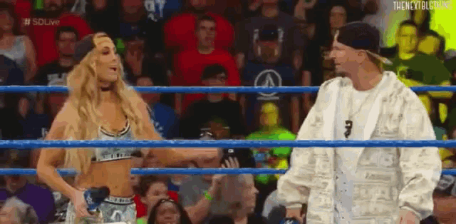a man and a woman are standing inside of a wrestling ring .