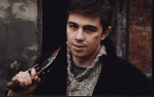 a man in a sweater is holding a shotgun