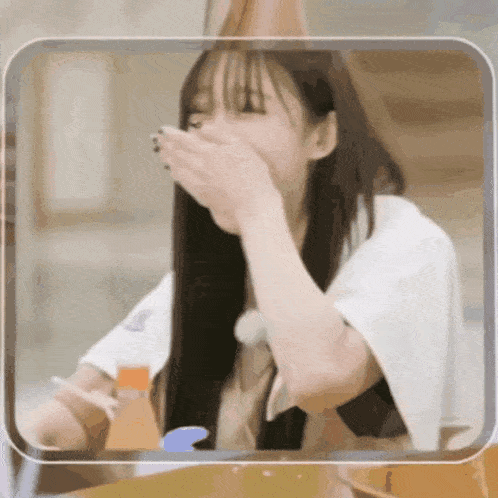 a woman with long hair is covering her mouth with her hands
