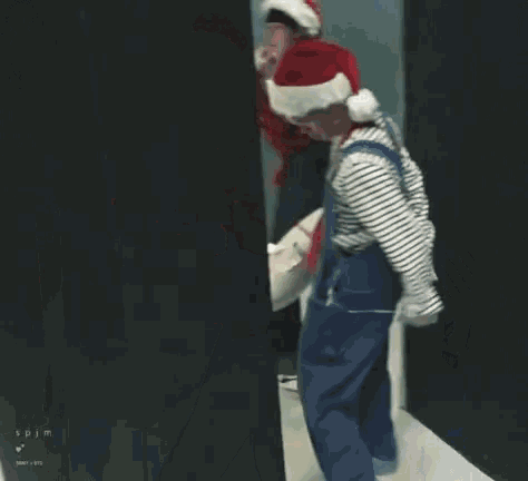 a man in overalls and a santa hat is dancing