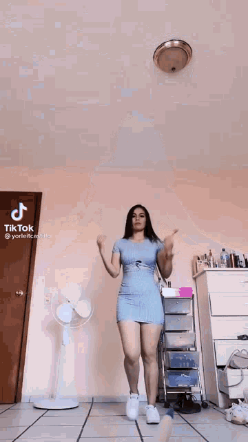 a woman in a short blue dress is standing in a room .